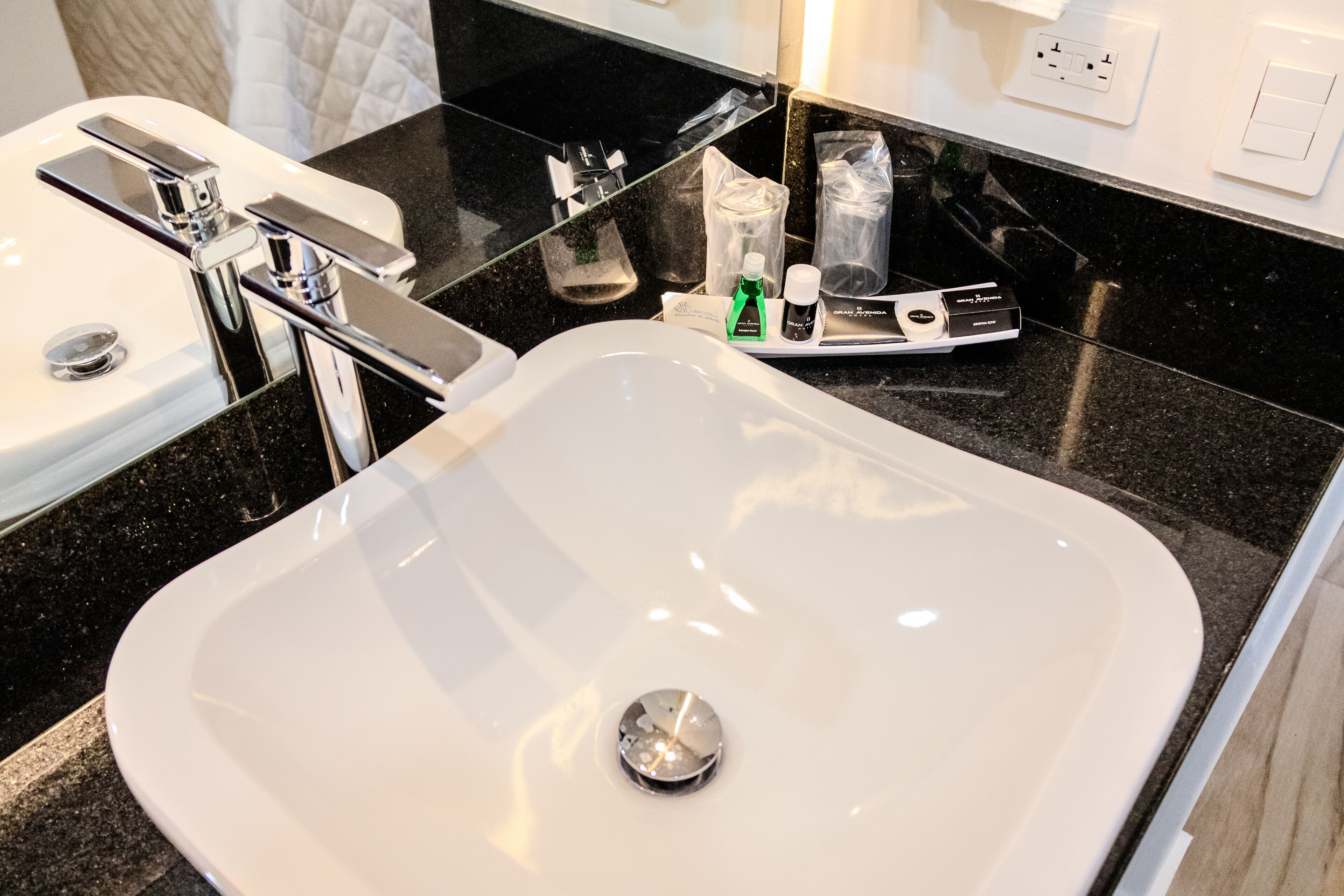 A modern bathroom with a white sink, chrome faucet, and a black countertop.