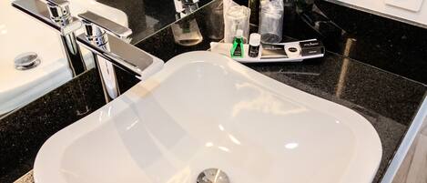 A modern bathroom with a white sink, chrome faucet, and a black countertop.