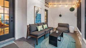 Ein gemütlicher Innenbereich mit einer Couch, einem Sessel und einem Couchtisch. An der Wand hängt ein Schild mit der Aufschrift 'Home is where the water meets the shore'.