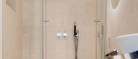 A modern bathroom with a glass-enclosed shower, a white toilet, and a glass sink.
