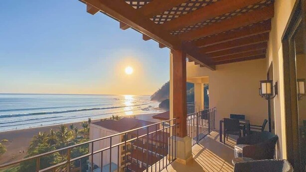 Een balkon met uitzicht op de oceaan en een heldere lucht.