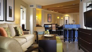 A living room with a sofa, coffee table, and a TV. There is a dining area with a table and chairs. - Beautiful St John Westin Villa - 2 bedroom Bay Vista (Cruz Bay)