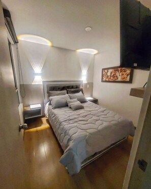 Une chambre moderne avec un grand lit, des tables de chevet et des lampes fixées au mur.
