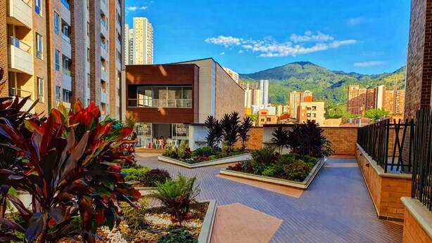Un edificio moderno con techo plano y un patio con plantas y zona de estar.