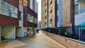 Una calle urbana moderna con una pasarela peatonal, edificios adyacentes y una valla de metal negro.