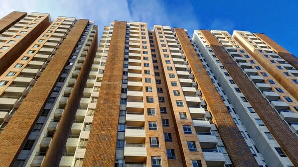 Un immeuble résidentiel de grande hauteur, composé de plusieurs étages, chacun étant doté de balcons et d’une façade en briques au style uniforme.