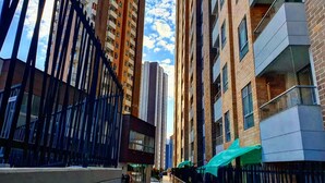 Una calle urbana moderna con edificios altos, una pasarela peatonal y un escaparate con toldo verde.