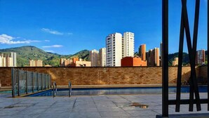 Un área de piscina en la azotea con vistas despejadas a edificios altos circundantes y colinas.