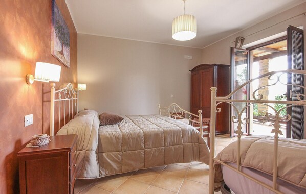 A bedroom with a bed, bedside table, lamp, and a window with shutters. - Gorgeous home in Torchiara (Torchiara)