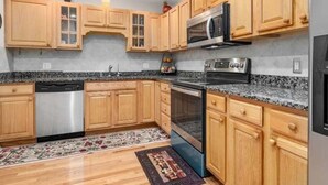 A kitchen with wooden cabinets, a dishwasher, a microwave, an oven, and granite countertops. - Beautiful two-story home close to downtown worcester 5beds-4bedroom (Worcester)