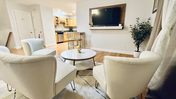 A living room with a round table, two armchairs, a TV mounted on the wall, and a potted plant. - Beautiful two-story home close to downtown worcester 5beds-4bedroom (Worcester)