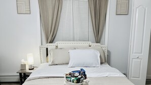 A neatly made bed with a headboard, a bedside table with a lamp, and a basket of toiletries on the bed. - Beautiful two-story home close to downtown worcester 5beds-4bedroom (Worcester)