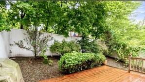 A wooden deck with a white fence and greenery in the background. - Beautiful two-story home close to downtown worcester 5beds-4bedroom (Worcester)