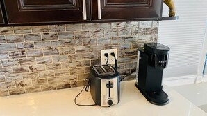 Eine Küche mit Steinrückwand, einem Toaster und einer Keurig-Kaffeemaschine auf der Arbeitsplatte.