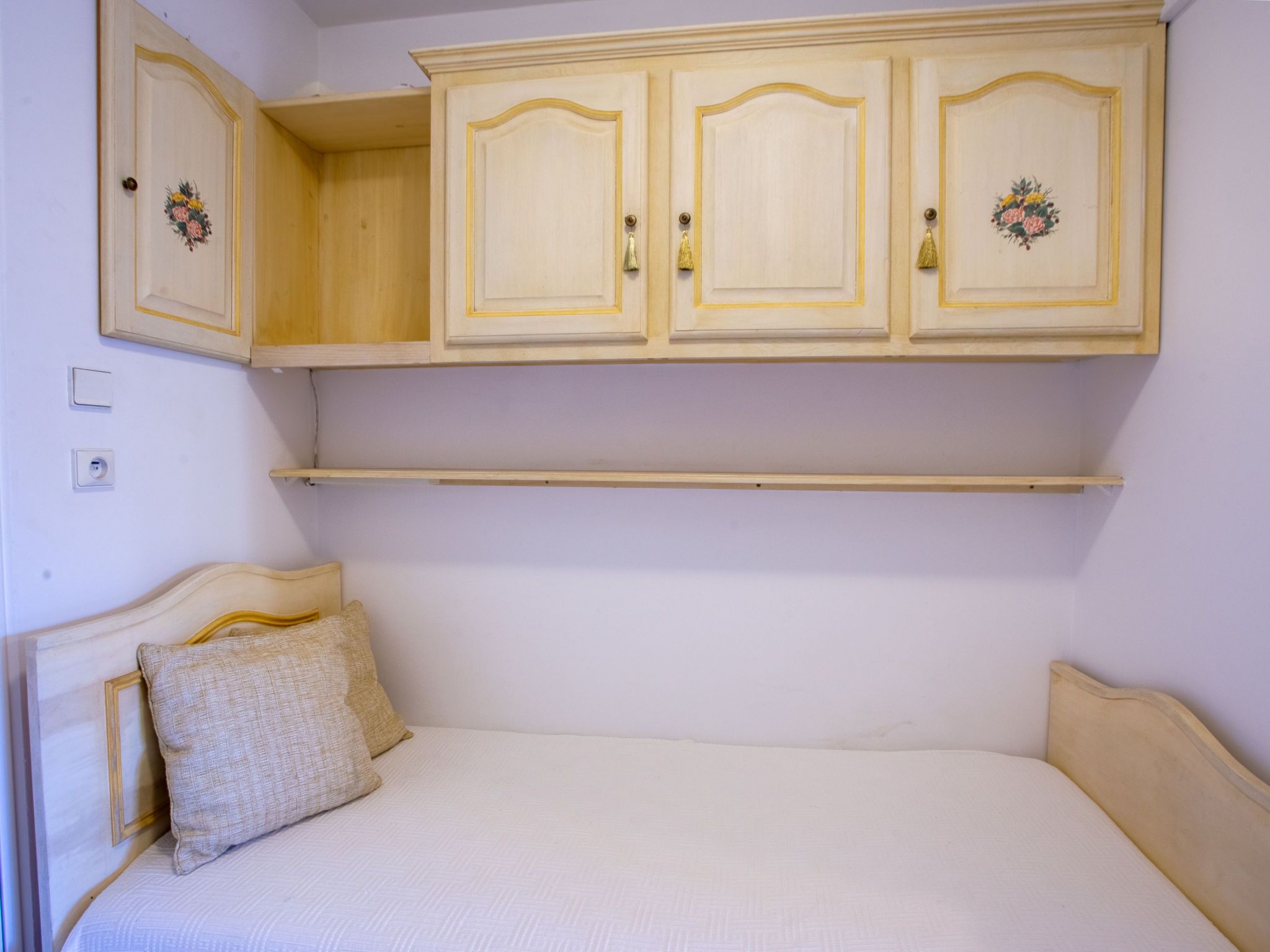 Quarto com cama, mesa de cabeceira e guarda-roupa com duas portas e prateleira.