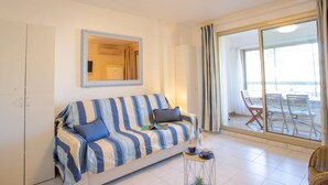 Una sala de estar moderna con un sofá a rayas, una mesita auxiliar y vistas a un balcón con mobiliario de exterior.
