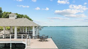 A gazebo with columns, a wooden deck, and a view of the water.