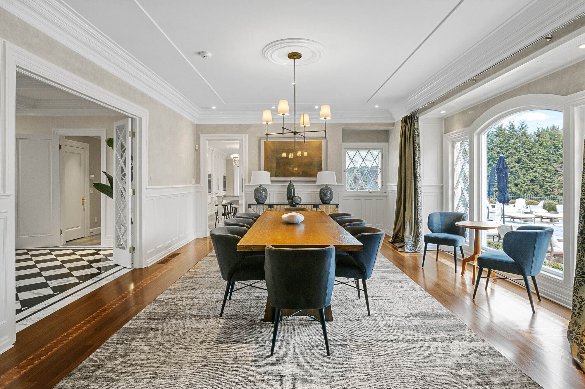 A dining room with a long wooden table, six chairs, and a chandelier.
