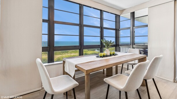A dining area with a table, chairs, and a view of the ocean.