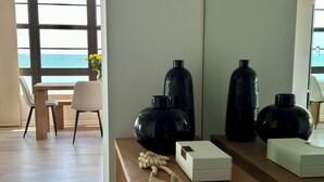 A modern room with a wooden desk, a chair, and a view of the ocean through large windows.