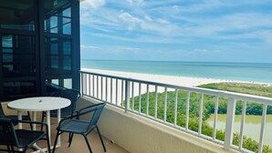 A balcony with a white railing, a round table, and two chairs.