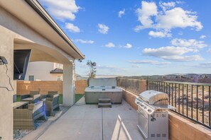 Un patio exterior con jacuzzi, parrilla y zona de estar.