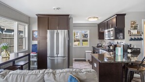 Una cucina moderna con frigorifero in acciaio inossidabile, pensili in legno scuro e un angolo caffetteria.