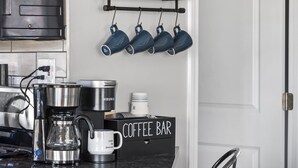 Una cucina con angolo caffè, comprensivo di macchina da caffè, tazze e insegna con scritto 'coffee bar'.