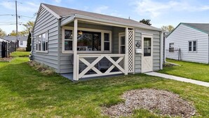 Una casa a un piano con veranda, garage e un piccolo giardino antistante.