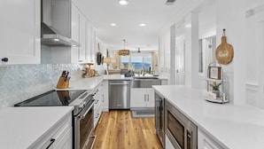 Une cuisine moderne avec des meubles blancs, des appareils en acier inoxydable et un plancher en bois.