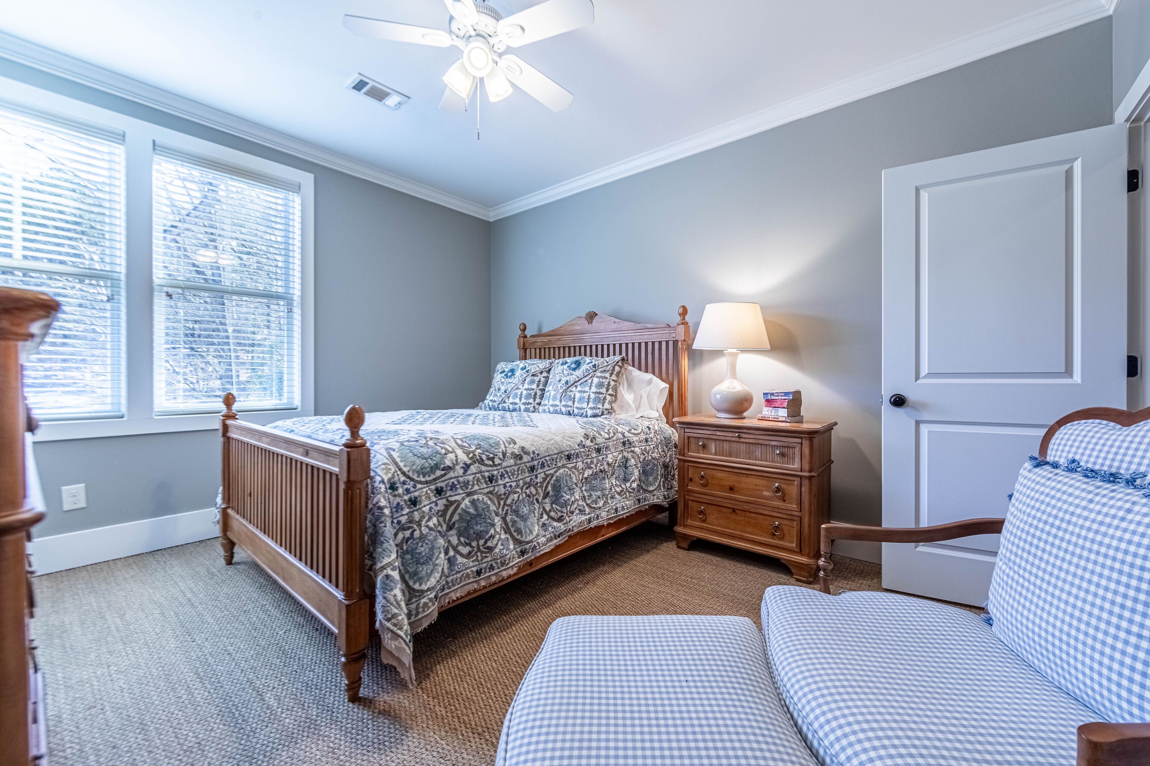 A bedroom with a wooden bed, a nightstand, a chair, and a door.