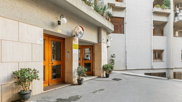 Un bâtiment avec une porte en bois, des plantes en pot et une enseigne indiquant qu’il s’agit d’un restaurant.
