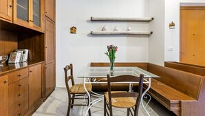 Un coin repas avec une table en verre, des chaises en bois, un banc et un vase rempli de fleurs.