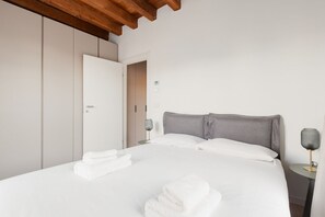 Una camera da letto con un letto, asciugamani bianchi, una lampada da comodino e un armadio.