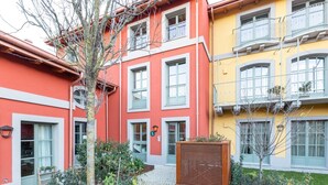 Un edificio de varios pisos con balcones, un pequeño jardín y una valla de madera.