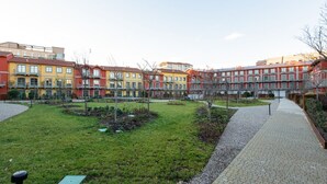 Un patio con césped, un sendero empedrado y edificios coloridos con múltiples ventanales.