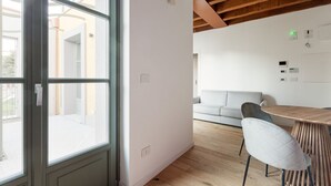 Un interior moderno con techo de madera, un comedor con mesa y sillas redondas, un sofá y un ventanal grande.