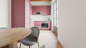 Una cocina estrecha con armarios rosados, un microondas y un horno.