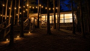 Eine Holzjagdhaus mit Treppe, umgeben von Bäumen, und Lichterketten.