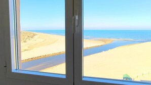 A window view of a beach with sand and water.