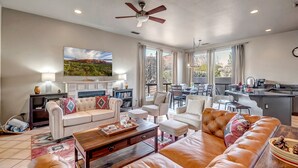 A spacious living room with a fireplace, a large TV, and a dining area with a kitchen in the background. - Experience luxury at Sedona Birdsong, a 3-bed retreat in Village of Oak Creek. (Sedona)