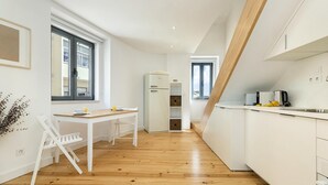 Una cocina moderna con armarios blancos, encimera de madera y horno empotrado.