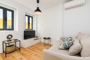 Un salon moderne avec un canapé, un téléviseur et une petite table d’appoint.