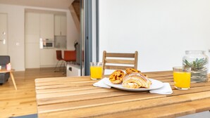 Una mesa de madera con pasteles y vasos de zumo de naranja.