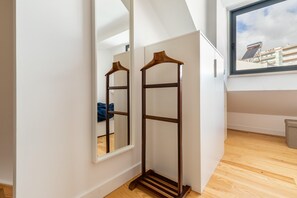 Una habitación con piso de madera, un espejo grande y una ventana con vista a edificios.