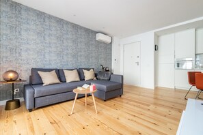 Una sala moderna con un sofá gris, una mesita de madera y una lámpara.