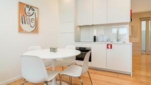 Ett modernt kök med vita skåp, ett matbord med fyra stolar och en mikrovågsugn.