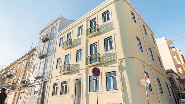 En byggnad med flera våningar, balkonger, en skylt som förbjuder parkering och en parkerad bil.