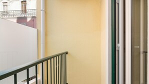 A balcony with a metal railing, a glass door, and a beige wall. - Arroios Concept III by Homing (Lisbon)