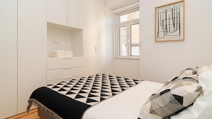 A bedroom with a bed, a wardrobe, a window, and a framed artwork on the wall. - Arroios Concept III by Homing (Lisbon)